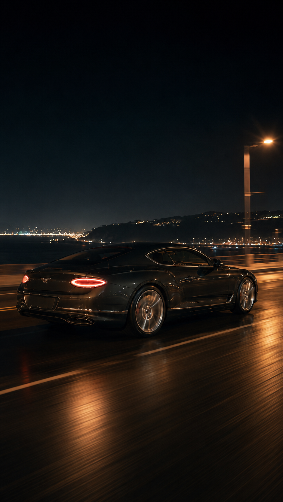 Bentley driving along the coast at night